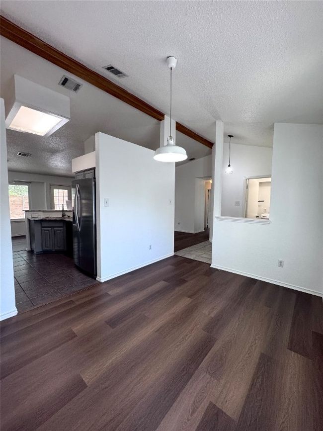 Unfurnished living room featuring a textured ceiling, dark wood finished floors, and vaulted ceiling | Image 6