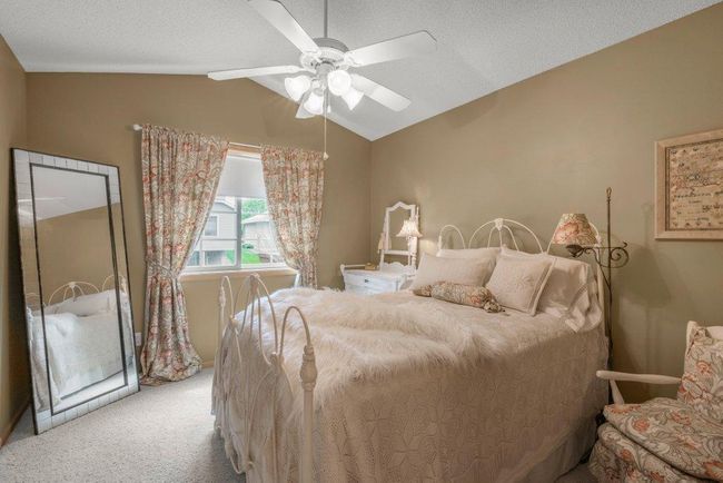 Secondary bedroom on upper level next to owner's suite with vaulted ceiling, adjustable speed ceiling fan, and walk-in closet. | Image 14