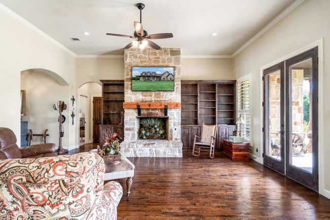 Living area with french doors, wood finished floors, ceiling fan, a fireplace, and crown molding | Image 13