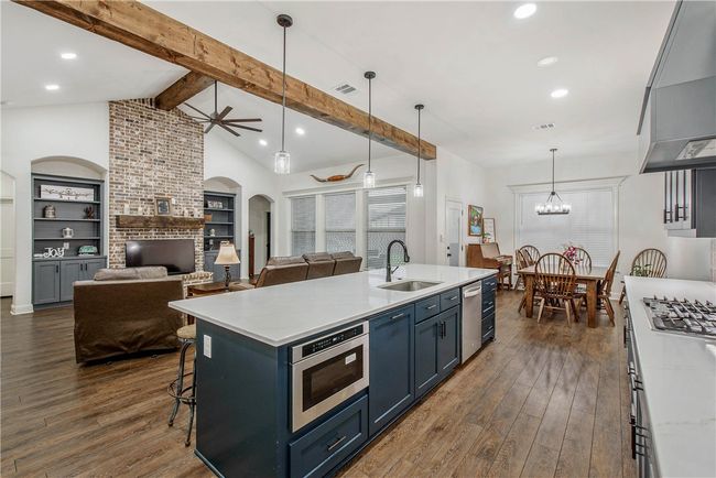 Kitchen with a sink, wall chimney range hood, appliances with stainless steel finishes, and wood-style floors | Image 11