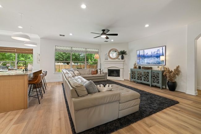 Living room featuring a glass covered fireplace, ceiling fan, recessed lighting, arched walkways, and light wood finished floors | Image 18