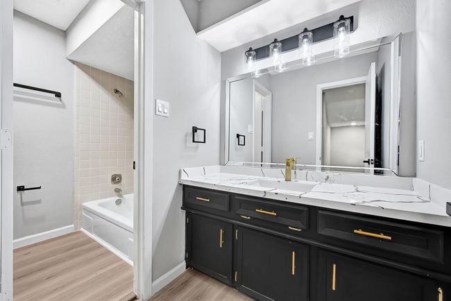 Full bathroom with updated vanity – Carrara-look quartz, gold faucet, and black cabinet. | Image 38