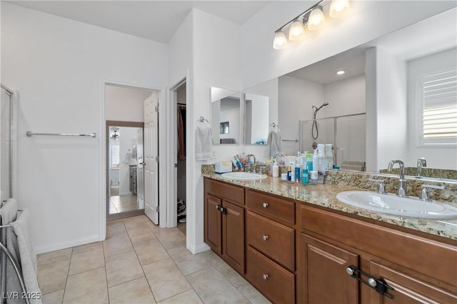 Full bathroom featuring double vanity, a shower with door, tile patterned flooring, and a sink | Image 27