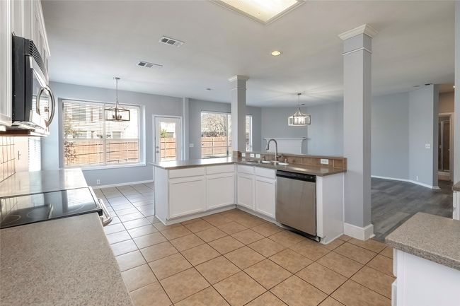 Kitchen featuring decorative columns, white cabinetry, stainless steel appliances, and decorative light fixtures | Image 22