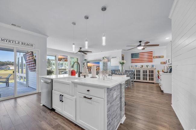 Kitchen featuring ceiling fan, stainless steel dishwasher, a sink, dark wood-style floors, and crown molding | Image 17