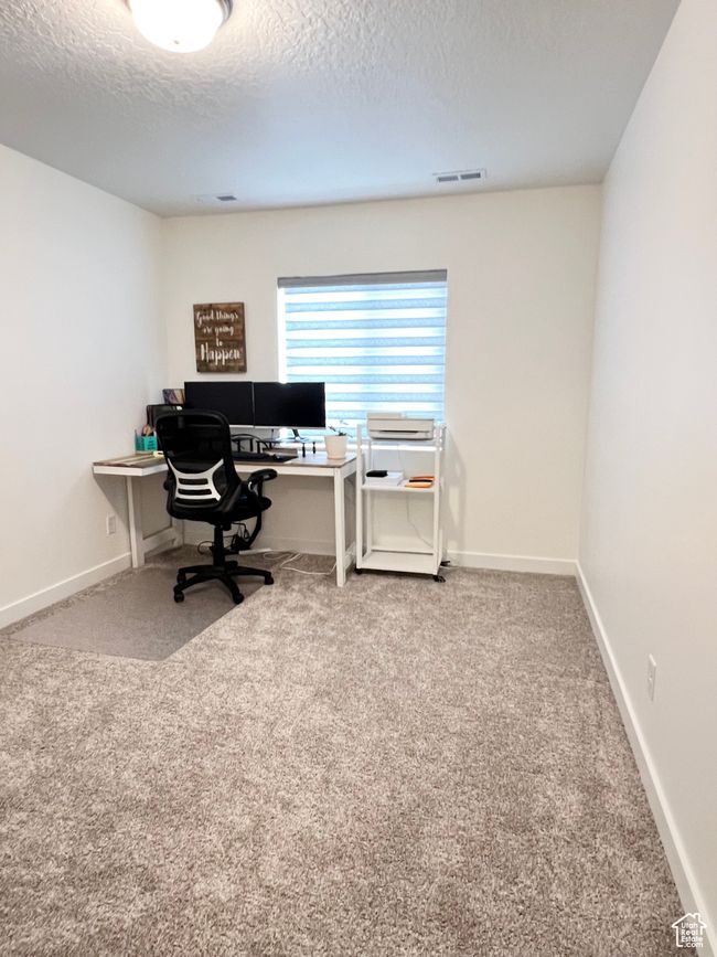 Carpeted office/bedroom space with a textured ceiling and walk-in closet | Image 16