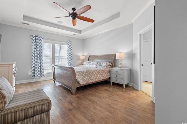 Bedroom featuring a tray ceiling, hardwood / wood-style flooring, ornamental molding, and a ceiling fan | Image 12