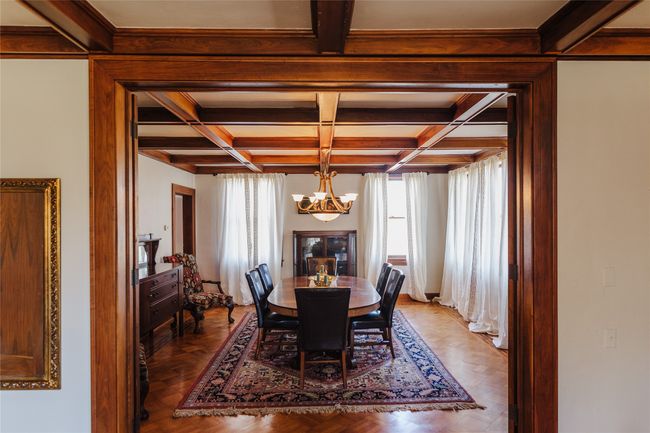 Dining room with beam ceiling, a chandelier, parquet floors, and coffered ceiling | Image 8