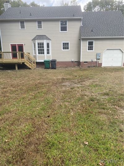 Rear view of property featuring a garage, a yard, and a wooden deck | Image 2