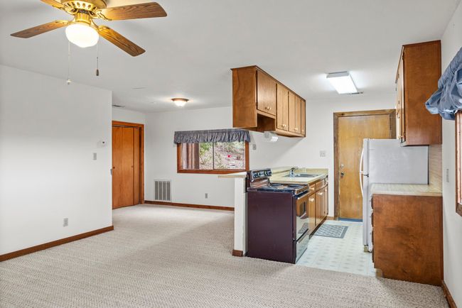 Kitchen with range with electric stovetop, light countertops, a ceiling fan, brown cabinets, and freestanding refrigerator | Image 30
