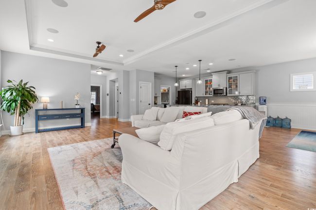 Living room with ceiling fan, light wood finished floors, a raised ceiling, and recessed lighting | Image 5