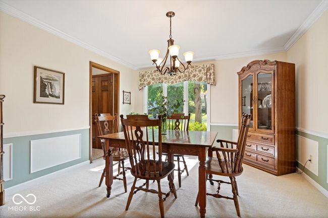 dining space featuring light carpet, crown molding, and a chandelier | Image 18