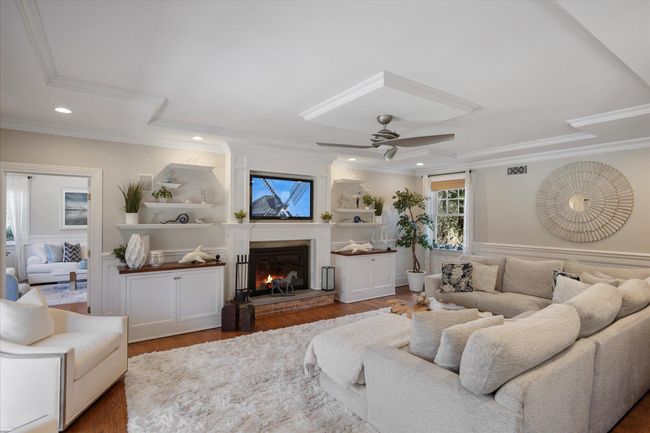 Living area with recessed lighting, ornamental molding, a ceiling fan, a glass covered fireplace, and wood finished floors | Image 15