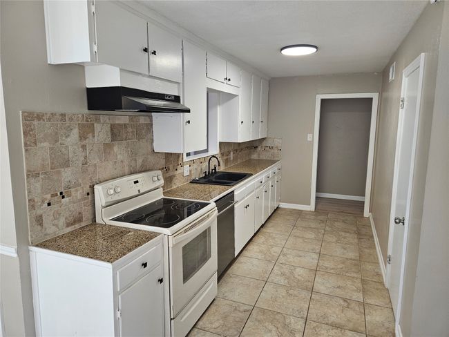Kitchen featuring tasteful backsplash, a sink, under cabinet range hood, electric stove, and stainless steel dishwasher | Image 4