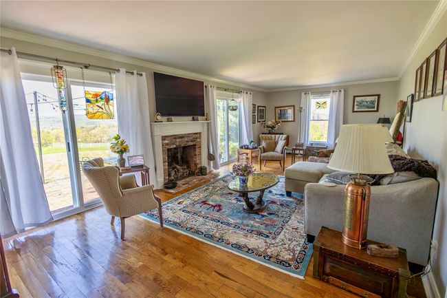 Living room with ornamental molding, wood finished floors, and a fireplace | Image 10