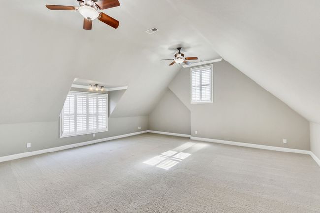 This expansive bonus room is a great play area, teen hang out, media room, exercise space or hideaway! Two sets of windows & two ceiling fans serve this over-a-3-car-garage sized recreation room. | Image 45