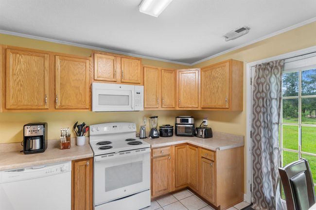 Kitchen featuring white appliances, light countertops, light tile patterned floors, and light brown cabinets | Image 8