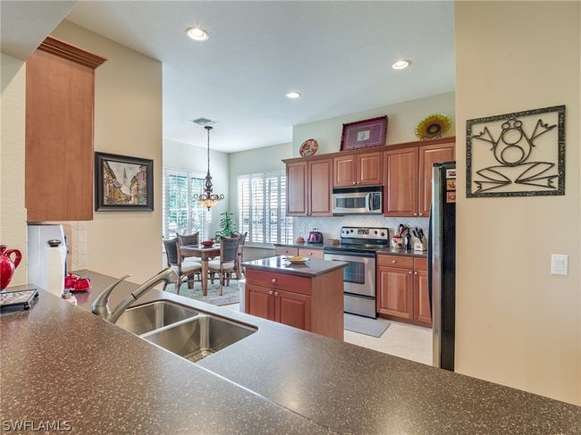 Kitchen with a kitchen island, appliances with stainless steel finishes, sink, tasteful backsplash, and light tile floors | Image 6