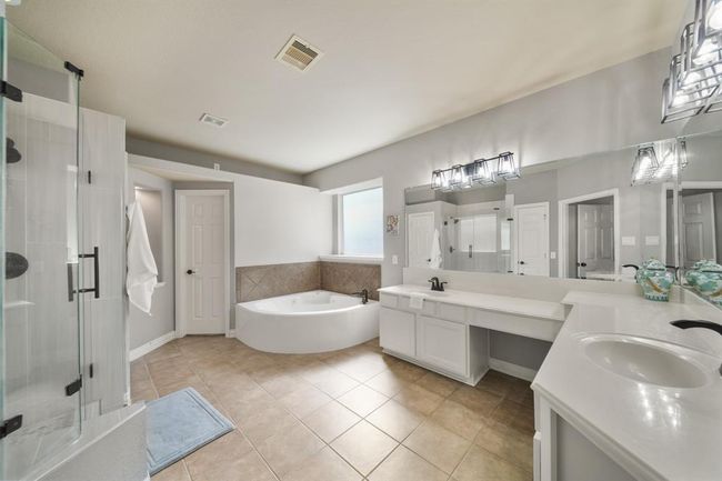 Luxury awaits you in this private bath complete with painted cabinets supporting solid surface counter tops with integrated back splashes, dual sinks, wall mounted mirror and lighting, a recessed & lighted art niche & tile flooring. | Image 24