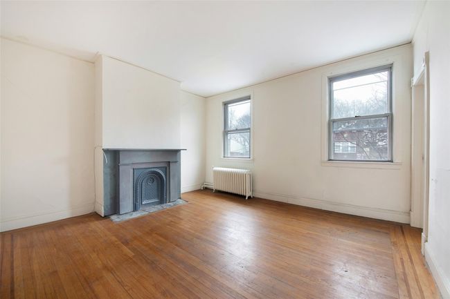 Unfurnished living room with wood-type flooring, a fireplace with flush hearth, and radiator | Image 8