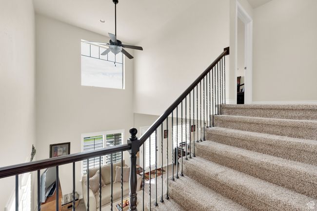Staircase featuring ceiling fan, plenty of natural light, a high ceiling, and carpet flooring | Image 13