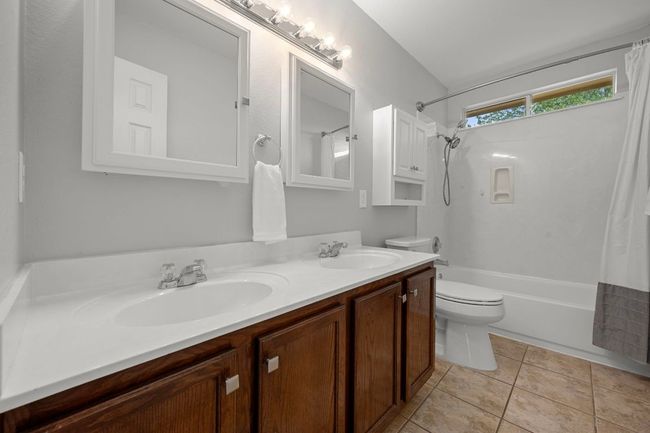Bathroom with toilet, double vanity, shower / bath combo, and tile patterned floors | Image 18