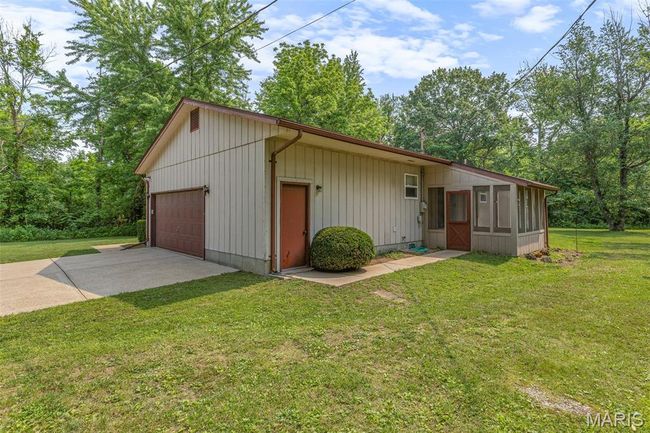 View of front facade featuring a front yard, driveway, and a garage | Image 8