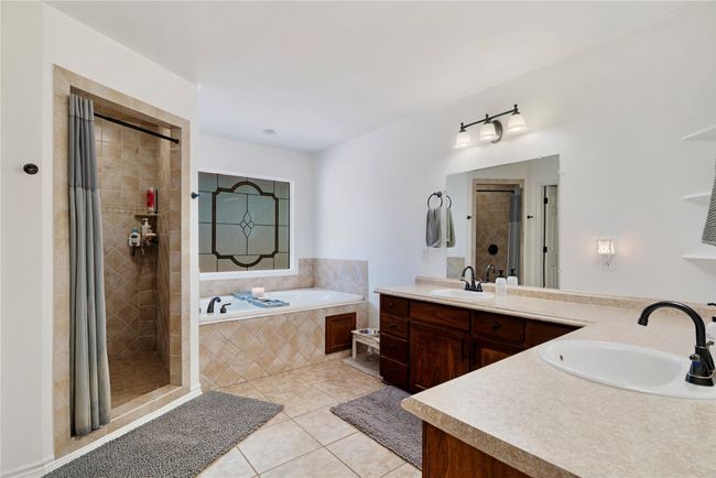 Bathroom featuring a bath, tile patterned floors, a sink, and a tile shower | Image 12
