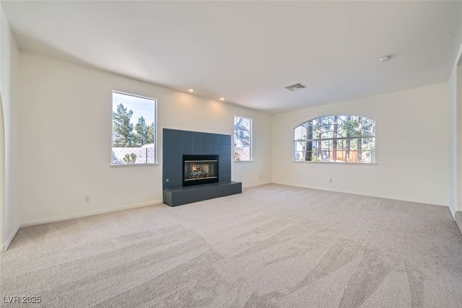 Unfurnished living room featuring baseboards, visible vents, light carpet, and a tiled fireplace | Image 23