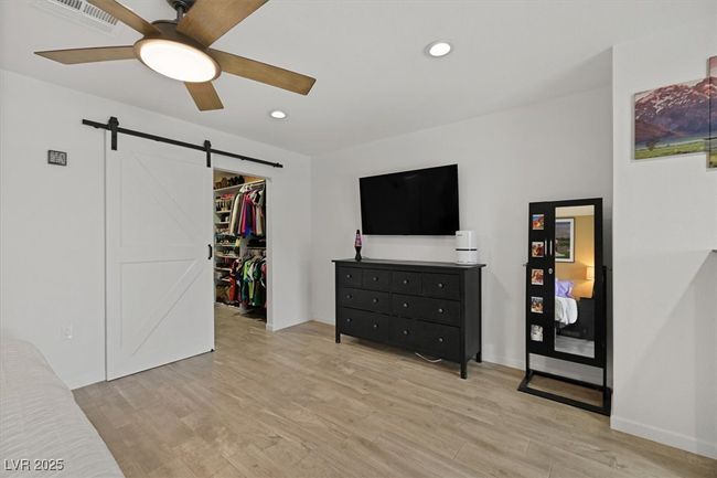 Bedroom with visible vents, light wood-style flooring, recessed lighting, a walk in closet, and a barn door | Image 16