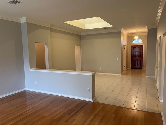 Spare room with wood finished floors, ornamental molding, and a skylight | Image 18