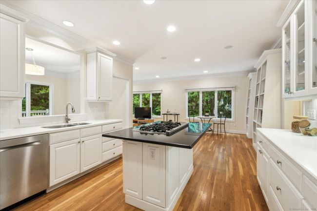 Bright, spacious kitchen with hardwood floors, SS appliances, and an abundance of white cabinetry. | Image 4