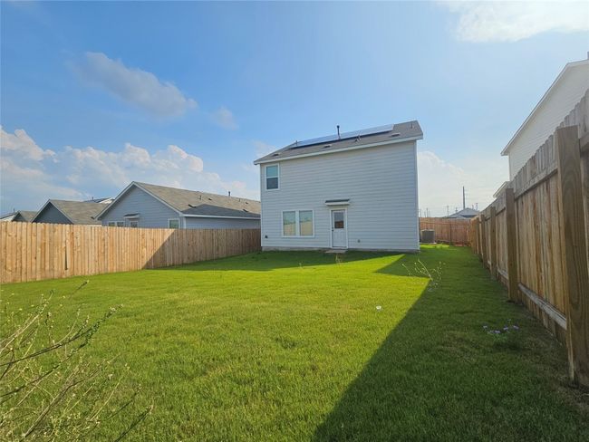 Back of house featuring roof mounted solar panels, a lawn, a fenced backyard, and central AC unit | Image 33