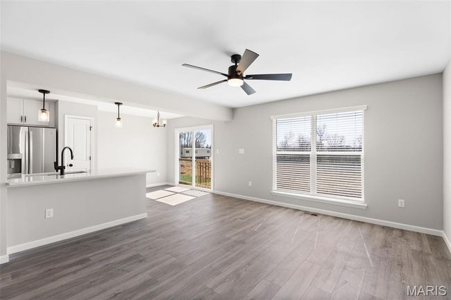 Unfurnished living room with baseboards, ceiling fan, dark wood-style flooring, and a sink | Image 8