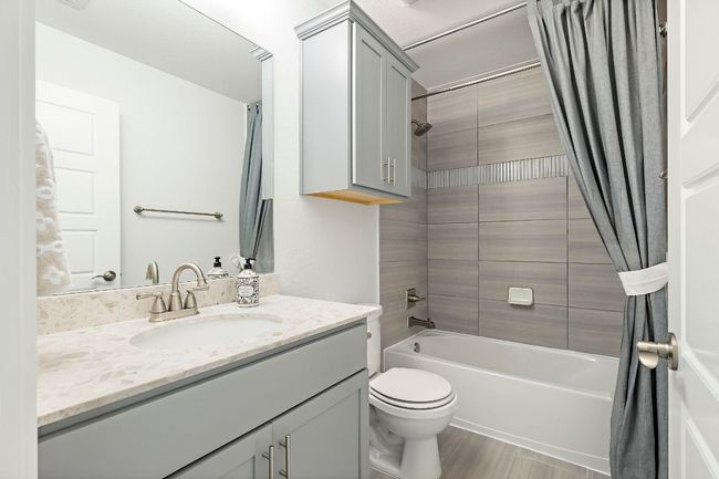 Full bathroom with shower / bathtub combination with curtain, toilet, and vanity | Image 26