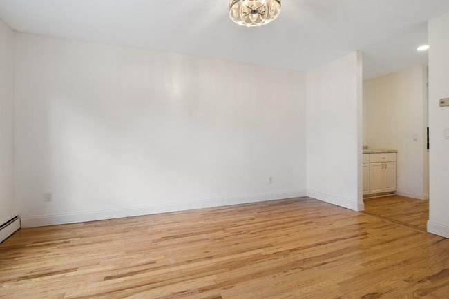 Empty room with light wood-type flooring, a chandelier, and baseboards | Image 4