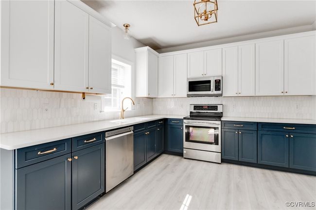 Kitchen with stainless steel appliances, blue cabinets, white cabinetry, and light wood-style floors | Image 15