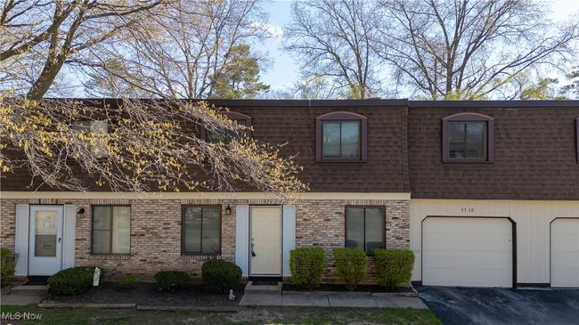 View of front of home with a garage, driveway, brick siding, and mansard roof | Image 21
