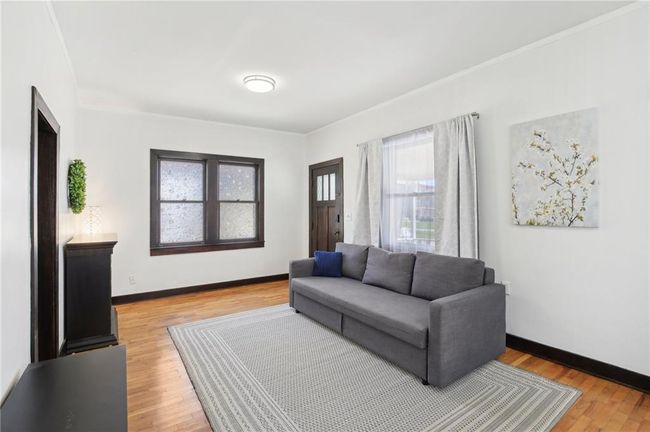Living room with baseboards, crown molding, and light wood-style floors | Image 6