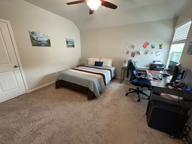 Carpeted bedroom featuring lofted ceiling, a desk, and ceiling fan | Image 9