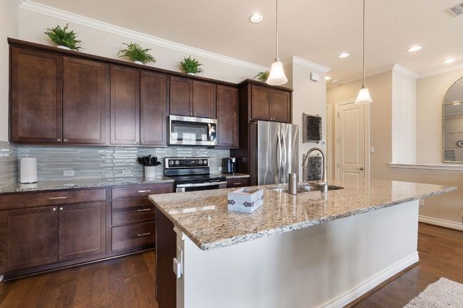 2nd Floor Kitchen featuring dark brown cabinetry, dark wood-type flooring, a sink, stainless steel appliances, and backsplash | Image 13