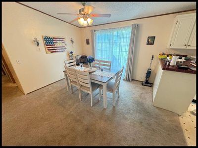 Dining space with a textured ceiling, ceiling fan, and light colored carpet | Image 3