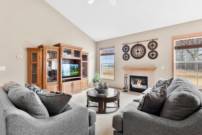 Two large windows frame the fireplace and fill the living space with natural light while offering a peaceful view of the backyard. | Image 8