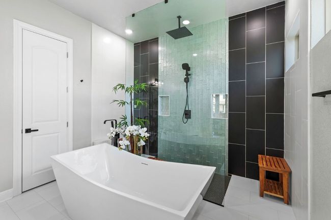 Stylish remodel primary bathroom featuring a freestanding bath, a dual walk in shower, tile patterned floors, and recessed lighting | Image 21