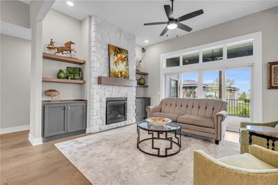 Living room featuring ceiling fan, light wood-type flooring, a fireplace, and built in features | Image 3