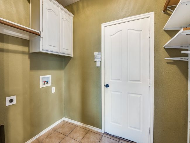 Laundry area with hookup for an electric dryer, light tile patterned floors, washer hookup, baseboards, and cabinet space | Image 14