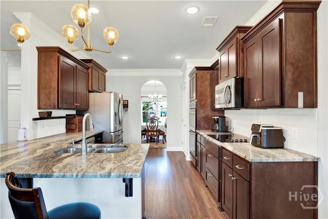 View of the Kitchen from the Breakfast Room looking into the Dining Room with arched doorway entrance. | Image 15