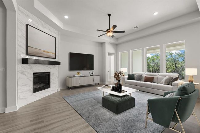 Soaring 12' ceilings and wide plank flooring frame this bright, open living space centered around a modern fireplace and matte-black floating mantel—perfectly blending casual comfort and refined design | Image 11
