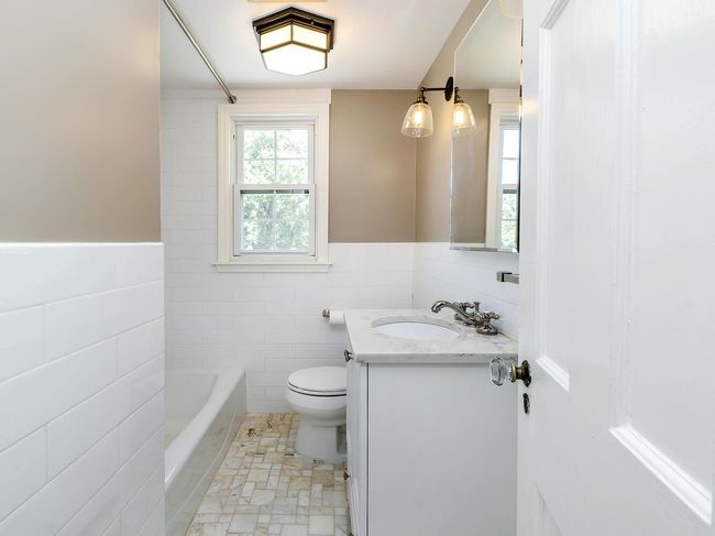 Bathroom with tile walls, vanity, a tub to relax in, toilet, and wainscoting | Image 20