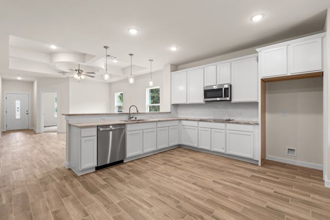 Kitchen featuring stainless steel appliances, a sink, a ceiling fan, a peninsula, and light wood-style floors | Image 16
